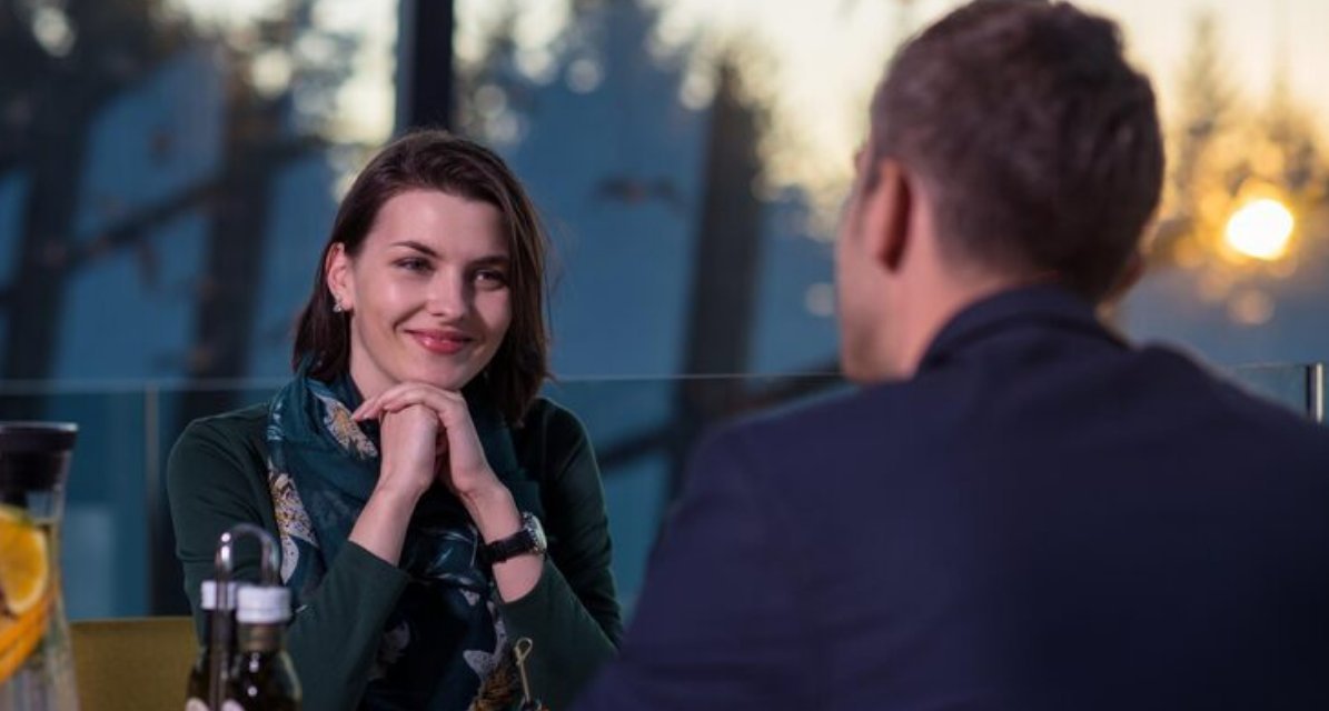 Couple in conversation at an outdoor bar as the sun sets